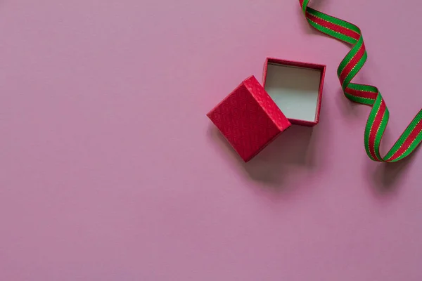Regalo rojo abierto o caja de regalo con cinta verde roja en la vista superior de la mesa rosa. Acostado. Concepto de cumpleaños, boda o Navidad . — Foto de Stock