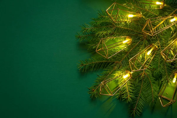 Fondo o concepto navideño, ramas de abeto verde y guirnalda luminosa sobre fondo verde — Foto de Stock