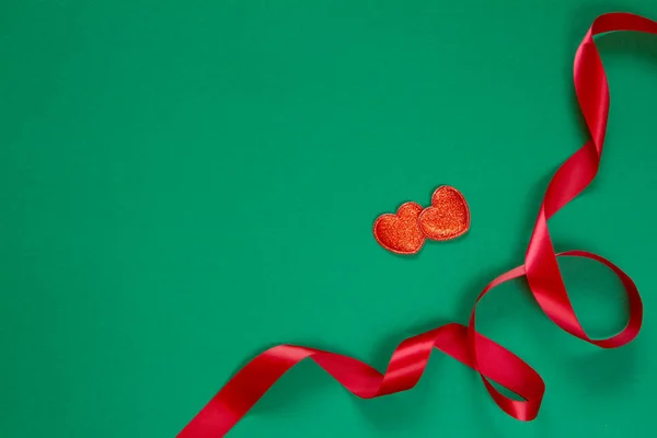 Delicado lazo rojo y dos figuras de corazón sobre fondo verde, Navidad o San Valentín concepto de decoración de vacaciones — Foto de Stock