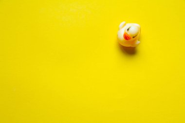 Sarı bir zemin üzerinde sarı plastik ördeğin üst görünümü, minimalist kavram veya arkaplan