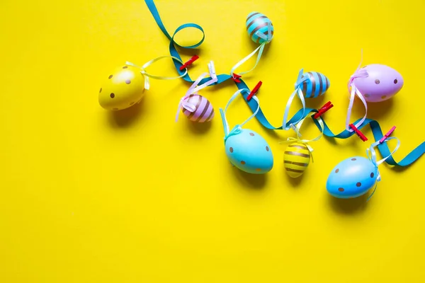 Decoración de Pascua, guirnalda de huevos de colores sobre un fondo amarillo brillante — Foto de Stock
