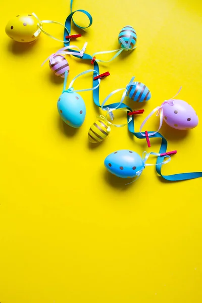 Decoración de Pascua, guirnalda de huevos de colores sobre un fondo amarillo brillante — Foto de Stock