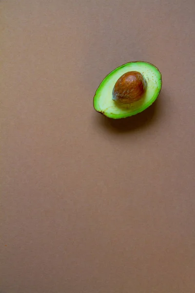 Hälfte rohe Avocado auf braunem Hintergrund, kreatives Essenskonzept — Stockfoto
