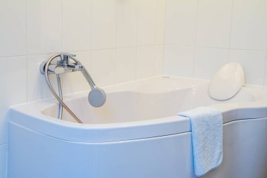 Başlığı, musluğu ve uzun hortumu olan modern köşe küveti kar beyazı iç banyoda seçici bir odak noktası var.