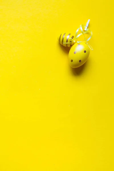Decoración de Pascua, dos huevos decorativos amarillos cosidos con cintas sobre un fondo amarillo brillante — Foto de Stock