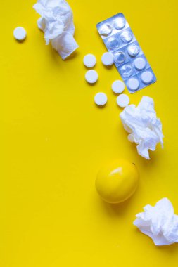 Lemon, sarı arka planda termometre ve beyaz tıbbi haplar, eczane teması, tedavi ve virüsün önlenmesi. Soğuk mevsiminde sağlık kavramı.