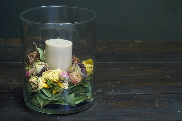 Vase en verre élément de décor en gros plan avec fleurs sèches et une bougie à l'intérieur sur une table en bois, mise au point sélective — Photo