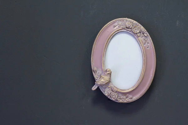 Empty pink-gold vintage oval frame in Victorian style on a gray wall, background or concept Royalty Free Stock Images