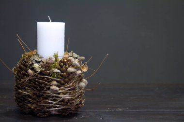 Ahşap bir yüzeyde beyaz mum bulunan kış dekorunun yakın çekimi, seçici bir odak