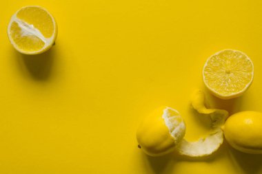 Sarı bir yüzey üzerinde bütün ve dilimlenmiş limonlar, sağlık ve vitamin kavramı.