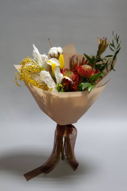 Kapalı bahar ruscus buketi, lökosendron, lökospermum, iris, pamuk, mimoza dalı, gri bir arka planda lale, seçici odaklanma