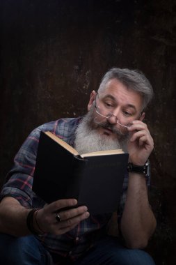 Beyaz saçlı, gözlüklü, kitap okuyan bir adamın portresi. Kapağında bir Rus yazısı. Bay Gorky, seçici odak noktası.