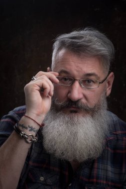 Stüdyo portresi. Beyaz saçlı, orta yaşlı, sakallı bir adam. Kameraya bakıyor.