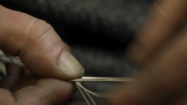 Yakın plan kuyumcu yeni bir ürüne başlıyor, gümüş bir bilezik dokuyor, seçici odaklanıyor.