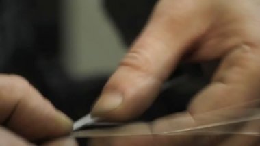 Yakın plan kuyumcu yeni bir ürüne başlıyor, gümüş bir bilezik dokuyor, seçici odaklanıyor.