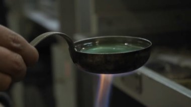 Yakın plan kuyumcu gümüş bir bileziği kimyasal çözeltide kaynatıyor, el yapımı gümüş mücevherler, seçici bir odak noktası var.