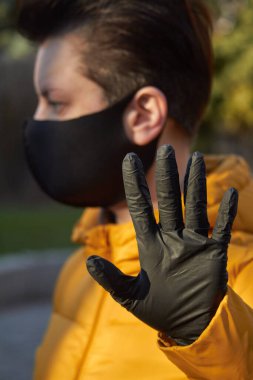 Korunaklı siyah maskeli orta yaşlı Avrupalı kadın Coronavirus COVID-19 salgını sırasında uyarı jesti yapıyor..