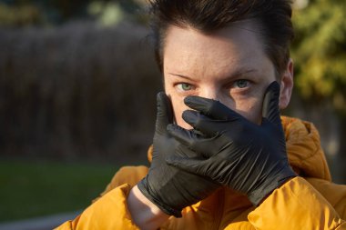 Korunaklı siyah eldivenli orta yaşlı Avrupalı bir kadın Coronavirus COVID-19 salgını sırasında uyarı jesti yapıyor.