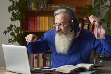 Mesafe öğrenme kavramı. Çılgın öğretmen dizüstü bilgisayarı karıştırıyor ve kravatına takıyor, seçici bir şekilde.