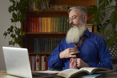 Mesafe öğrenme kavramı. Öğretmen kravat takar ve online ders için hazırlanır. Olgun sakallı adam çevrimiçi eğitime hazırlanıyor.