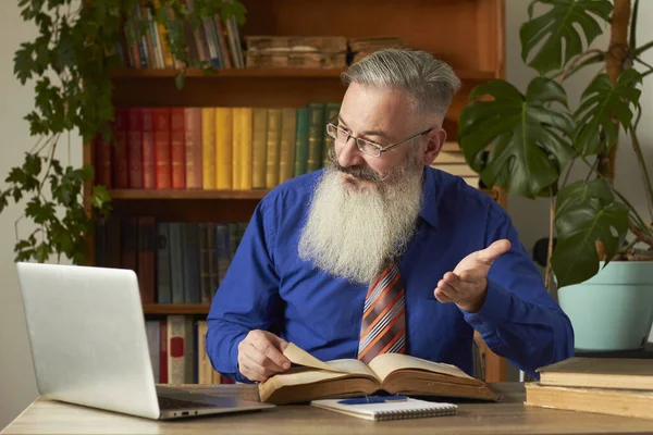 Uzaktan Öğrenme Konsepti. Öğretmen profesör çevrimiçi disiplin öğretiyor. Olgun gri sakallı adam öğretmenin sorusunu dizüstü bilgisayarla cevaplıyor..