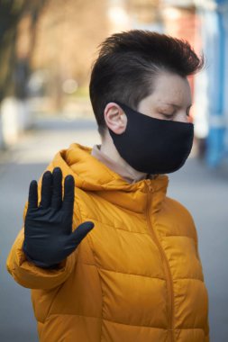 Korunaklı siyah maskeli orta yaşlı Avrupalı kadın Coronavirus COVID-19 salgını sırasında uyarı jesti yapıyor..