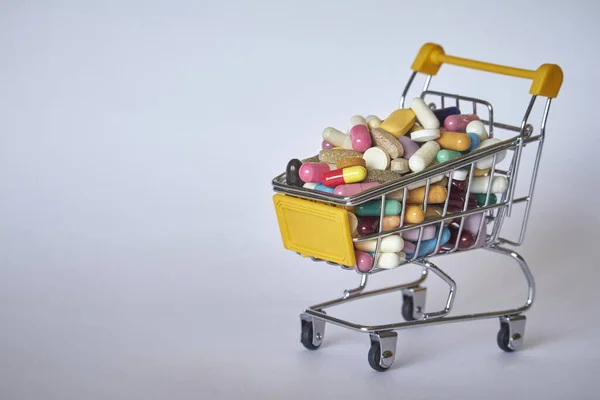 Medical background or concept. Close-up of a shopping trolley filled with colorful pills. Cart from the supermarket with different medicines.