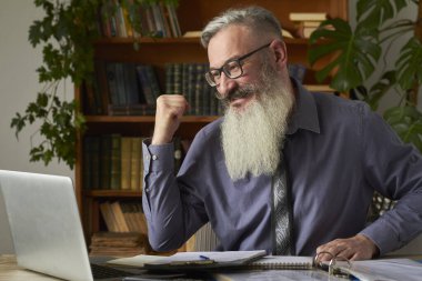 Mesafe öğrenme kavramı. Öğretmen dizüstü bilgisayara bakıyor ve zafer jesti gösteriyor, seçici odaklanma