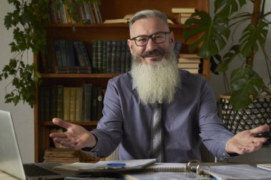 Mesafe öğrenme kavramı. Öğretmen kameraya bakıyor ve davetkar bir jest yapıyor, seçici bir odak noktası.