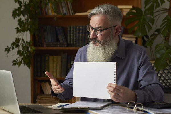 Concept of distance learning. Teacher, translator, tutor at the desktop in library shows blank plate at laptop screen, selective focus