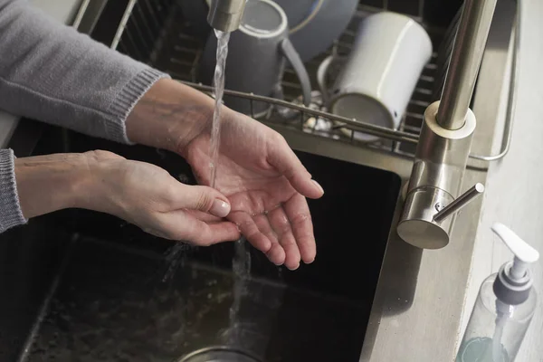 Hygiene concept, top view woman washes hands in kitchen sink and wipes her hands with towel, selective focus