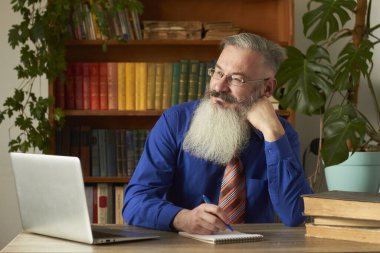 Uzaktan Öğrenme Konsepti. Öğretmen profesör çevrimiçi disiplin öğretiyor. Olgun gri sakallı adam öğretmenin sorusunu dizüstü bilgisayarla cevaplıyor..