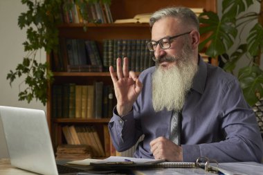 Mesafe öğrenme kavramı. Öğretmen öğretmen dizüstü bilgisayara bakıyor ve interlocutor Tamam işareti, seçici odaklanma gösterir