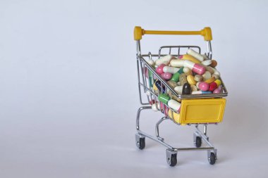 Tıbbi geçmiş ya da konsept. Renkli haplarla dolu alışveriş arabasının yakın çekimi. Marketten alınmış farklı ilaçlarla dolu bir araba..