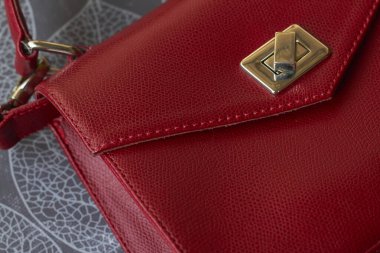 Gri arka planda altın elementli kırmızı deri çanta. Logo veya reklam için boş alan.