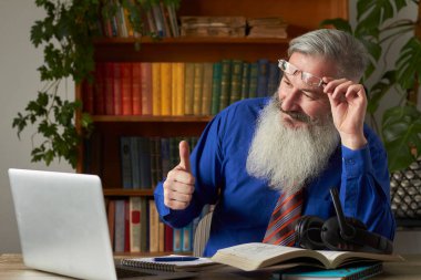 Mesafe öğrenme kavramı. Öğretmen dizüstü bilgisayara bakıyor ve parmağını kaldırıyor, seçici odaklanıyor.