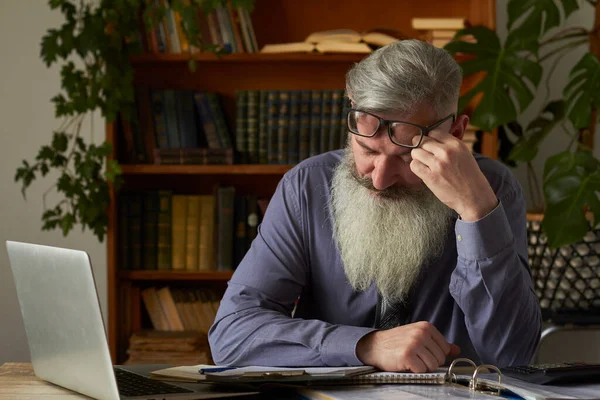 Mesafe öğrenme kavramı. Laptop ve masaj tapınağına bakan yorgun öğretmen, seçici odaklanma