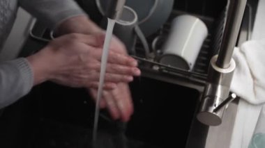 Hijyen konsepti, üst düzey kadın mutfak lavabosunda ellerini yıkar ve ellerini havluyla siler.