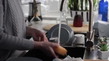 Kadın ellerinin mutfak lavabosunda bulaşıkları yıkaması, sabunlanması, durulaması, seçici odaklanma.