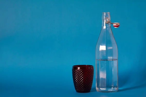Скляна Пляшка Прозорою Водою Червоним Склом Синьому Фоні Вибірковий Фокус — стокове фото