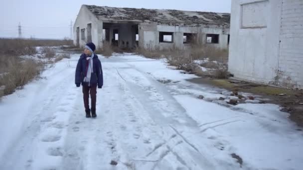 De jongen is in de buurt van de verwoeste boerderij — Stockvideo