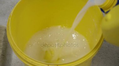 İşçi sıvı bir kova içine dökülen.