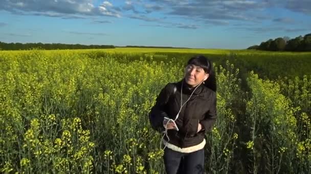 La ragazza sta camminando sul campo di colza — Video Stock