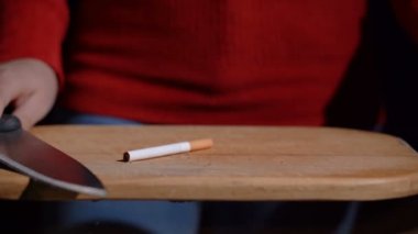 Kız sigarayı bıçakla kesiyor.