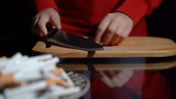 Девушка режет сигарету ножом — стоковое видео