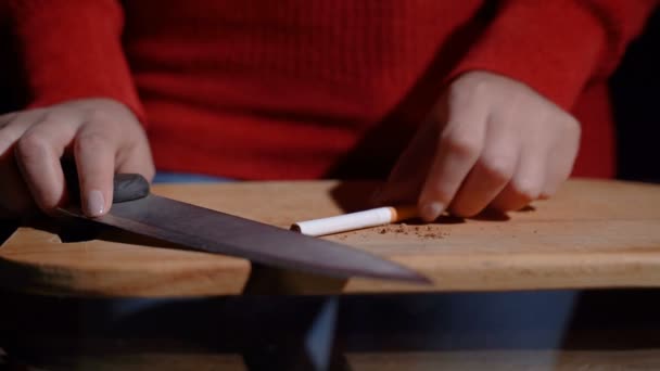 The girl cuts a cigarette with a knife — Stock Video