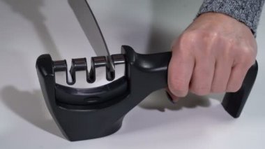 Bir kız bileyiciyle bıçağı keskinleştirir.