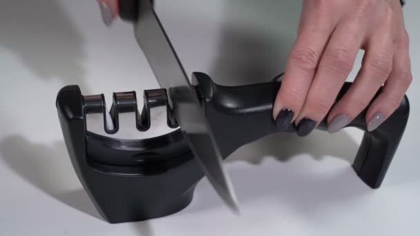 A girl sharpens a knife with a sharpener — Stockvideo