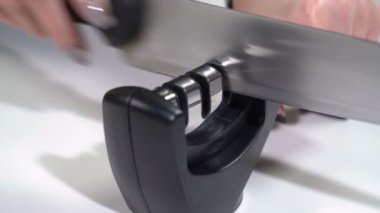 Bir kız bileyiciyle bıçağı keskinleştirir.