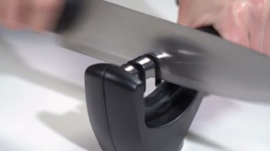 Bir kız bileyiciyle bıçağı keskinleştirir.